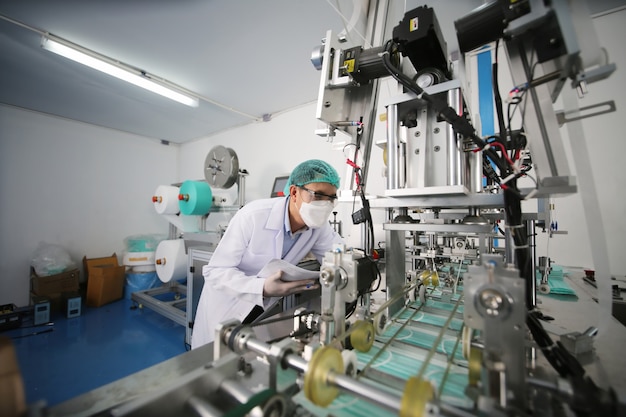 Trabajador de control de calidad analizando la máquina de fabricación en laboratorio.