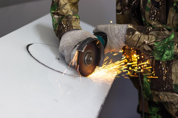 un trabajador corta un círculo de metal con una amoladora angular