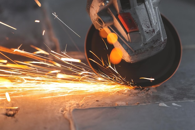 Un trabajador corta metal con un molinillo de chispas rojas brillantes