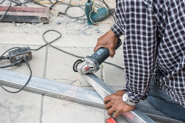 Trabajador corta un tubo de metal con algún aparato o aparato eléctrico