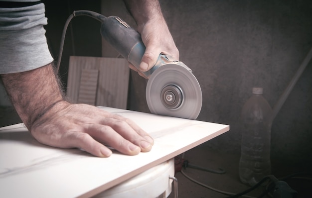 Trabajador cortando un azulejo con una amoladora.