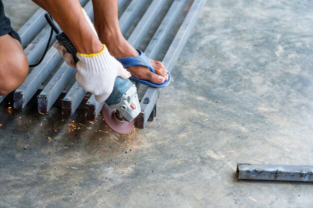 Foto trabajador cortando metal con molinillo con chispas.