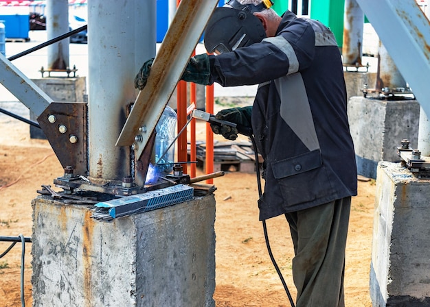 Foto trabajador cortando placa de metal con soplete de corte de gas en un sitio de construcción instalación de una estructura metálica primer plano el soldador realiza la instalación de estructuras metálicas chispas de soldadura