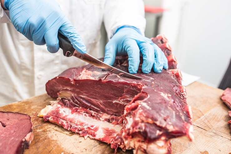 Trabajador de cuchillo cortando carne en una tienda de carne.
