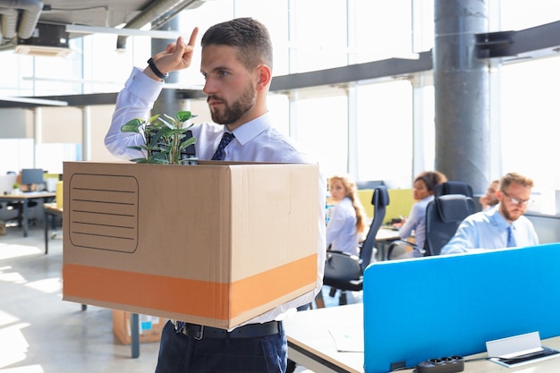 Trabajador despedido saliendo de la oficina con su material de oficina mostrando follar