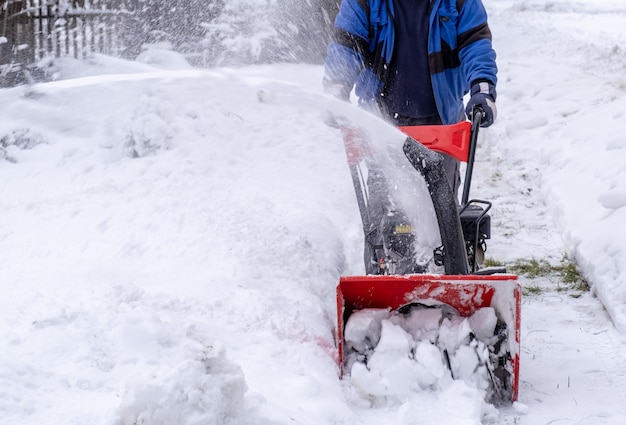 Trabajador despeja fácilmente la calle o el jardín de la nieve con un quitanieves en invierno