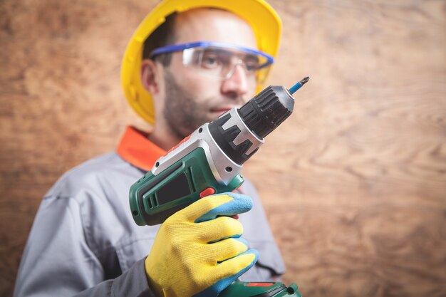 Foto trabajador con destornillador inalámbrico en pared de madera