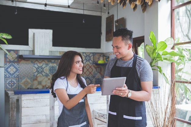 Trabajador de dos cafés usando tableta juntos