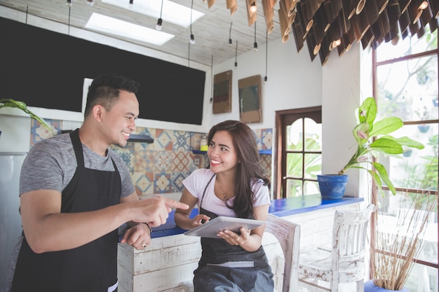 Trabajador de dos cafés usando tableta juntos