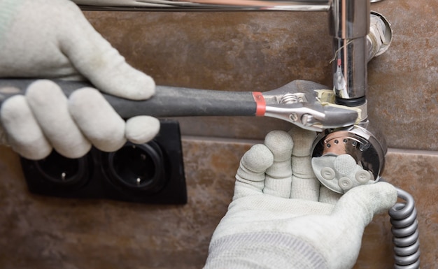 Un trabajador está instalando un elemento calefactor en el calentador de toallas del baño.