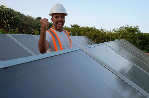 trabajador eufórico del panel solar con el puño en el aire mientras mira la cámara