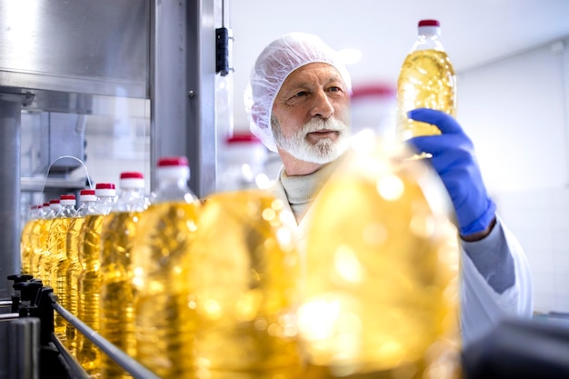 Trabajador experimentado de la línea de producción que controla el proceso de producción de aceite vegetal en la fábrica de alimentos