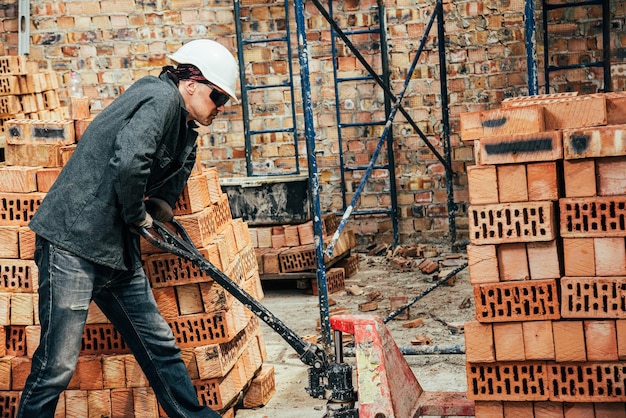 Foto un trabajador experimentado trabaja en la construcción de una casa de ladrillos.