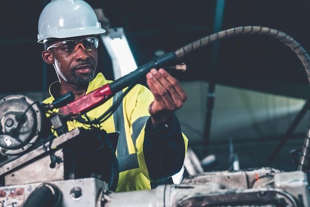 Trabajador de una fábrica afroamericana que trabaja con un brazo robótico experto