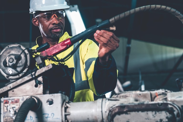 Trabajador de una fábrica afroamericana que trabaja con un brazo robótico experto