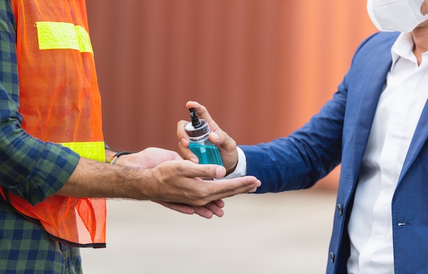 Trabajador de la fábrica de cerca usando gel de alcohol o desinfectante para manos en el sitio de construcción