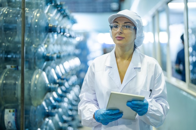 Foto trabajador de la fábrica comprobando botellas de agua en el almacén de la fábrica industrial