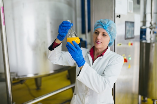 Trabajador en fábrica de embotellado comprobando la calidad del jugo.