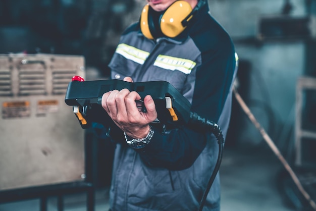 Trabajador de fábrica joven que trabaja con el brazo robótico adepto