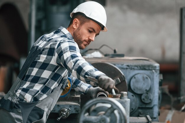 Foto el trabajador de la fábrica de la máquina operativa en uniforme está en el interior