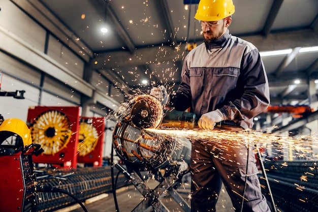 Un trabajador de una fábrica de metal y hierro que procesa la construcción de metal con un molinillo