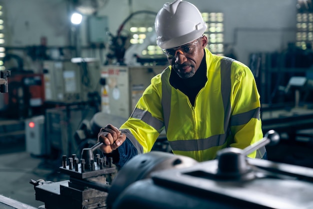 Foto trabajador de fábrica o ingeniero hace trabajo de máquina en taller de fabricación experto