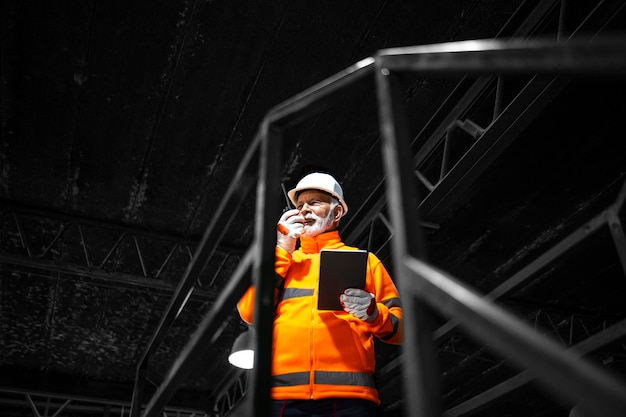 Foto trabajador de fábrica que utiliza comunicación por radio y controla la producción en la fábrica de fabricación industrial