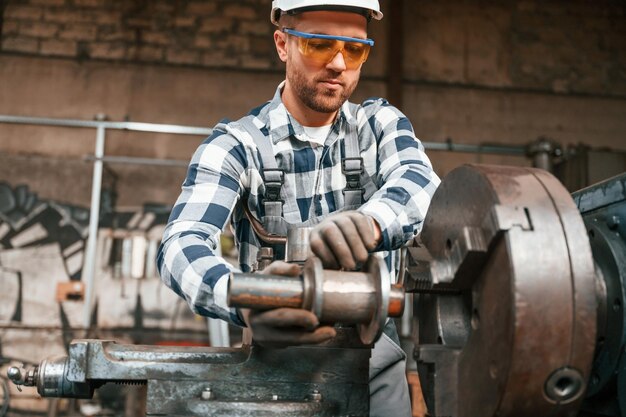 Foto el trabajador de fábrica uniformado está en el interior procesando en el metal