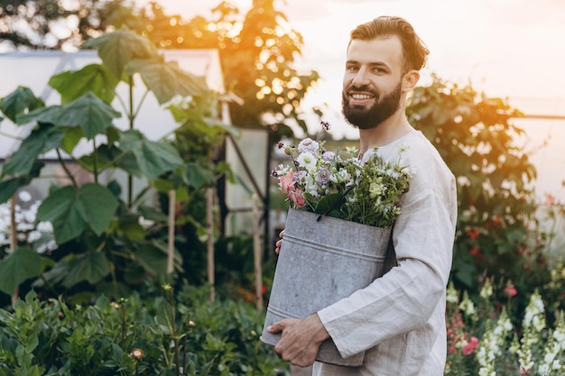 Un trabajador feliz en una plantación de flores que se dedica a su trabajo favorito cultivando y cuidando flores Riega y corta flores para ramos de flores