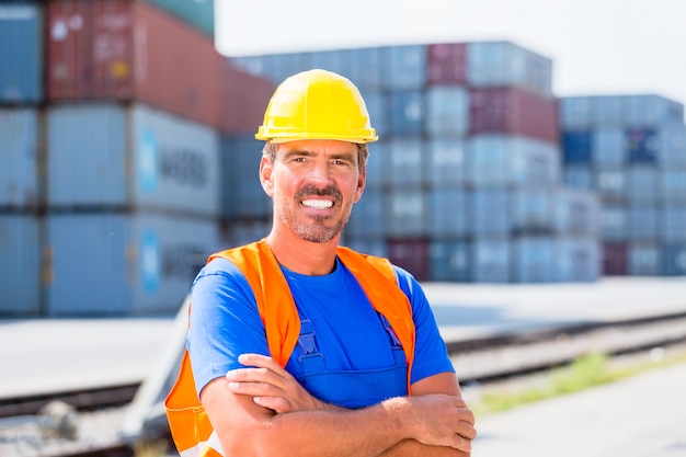 Trabajador y fila de contenedores en puerto.