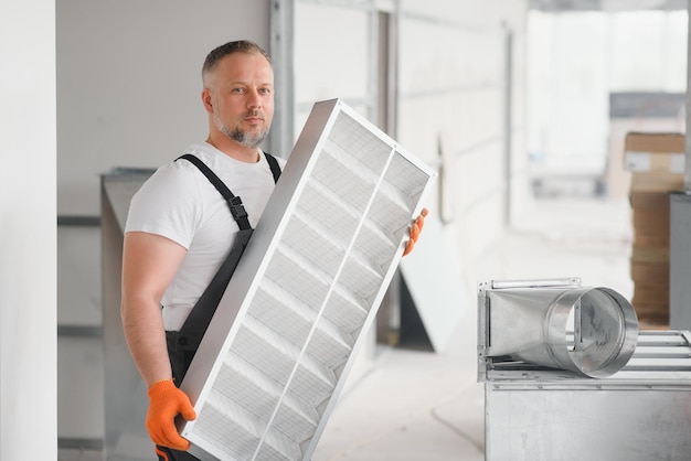 Trabajador con filtro de aire para instalar en el sistema de ventilación de la oficina Concepto de pureza del aire