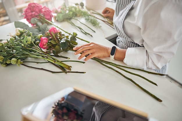 Trabajador de floristería calificado tocando flores en la mesa