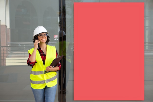 Trabajador hablando por teléfono sonriendo, cartel rectangular rojo en el fondo