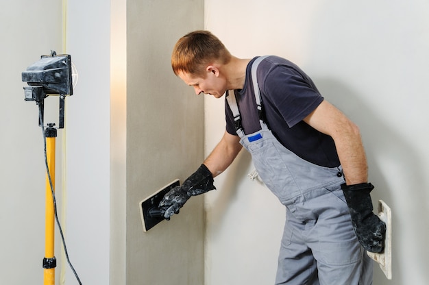 El trabajador hace el alisado final en la pared.