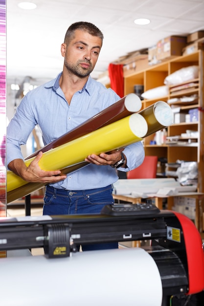 Trabajador de impresión masculino con rollos de papel de colores