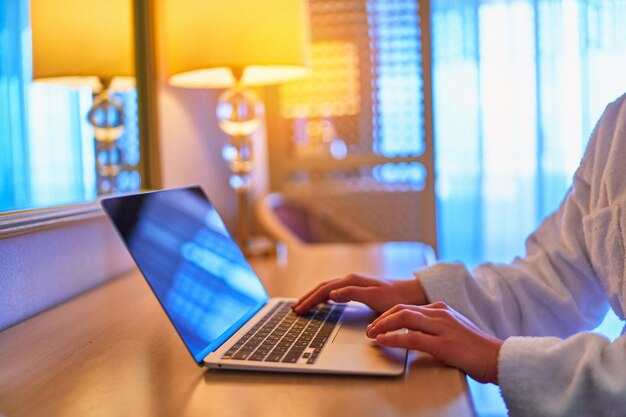 Trabajador independiente que usa una computadora portátil para trabajar a distancia en línea en una habitación de hotel