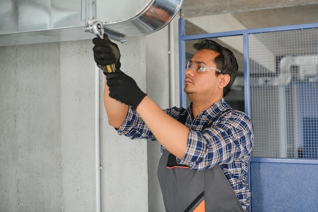 Trabajador indio instala un sistema de tuberías de conductos para ventilación y aire acondicionado copia del espacio