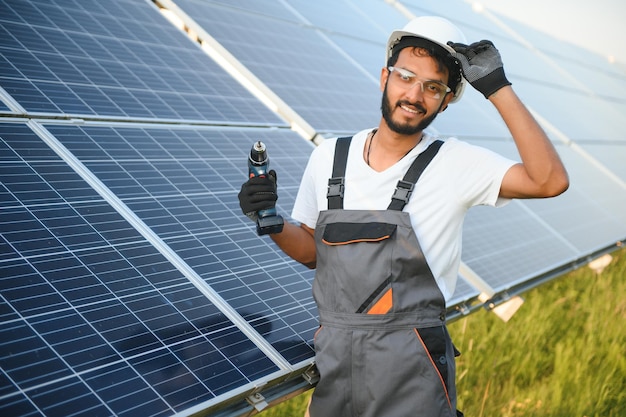 Un trabajador indio uniformado y con herramientas trabaja en una granja de paneles solares.