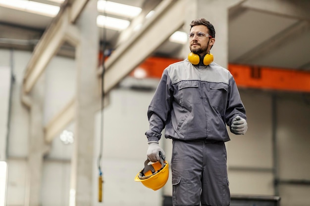 Un trabajador de la industria pesada camina por las instalaciones y mira a su alrededor.