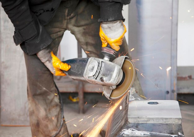 Trabajador de la industria pesada cortando acero con una amoladora angular