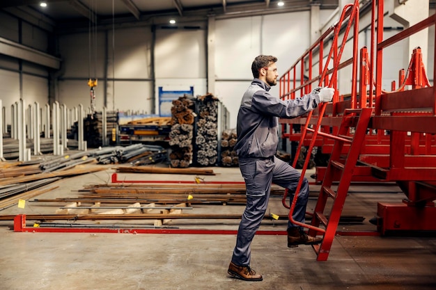 Un trabajador de la industria pesada está subiendo a una máquina de procesamiento de metales