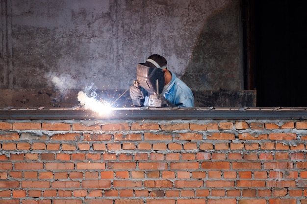 Trabajador de la industria soldando piezas de hierro en nuevo edificio