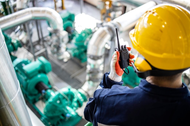 Trabajador industrial en equipos de seguridad comprobando la producción de petróleo y gas en la planta de refinería