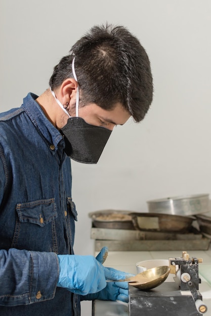 Trabajador industrial masculino con máscara protectora sosteniendo una espátula realiza pruebas en el laboratorio de geología