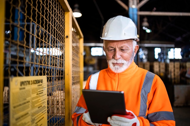 Trabajador industrial o supervisor que controla el proceso de producción a través de una tableta en la fábrica.