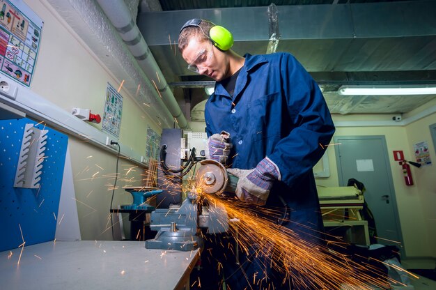 Foto trabajador industrial pesado en fábrica de metal con herramienta de rectificado eléctrico