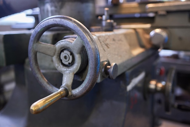 El trabajador industrial pesado de mano cercana está trabajando en el proceso de la fábrica de trabajo del metal realizando una operación de torneado mecánico en la máquina para la industria de la estructura de acero