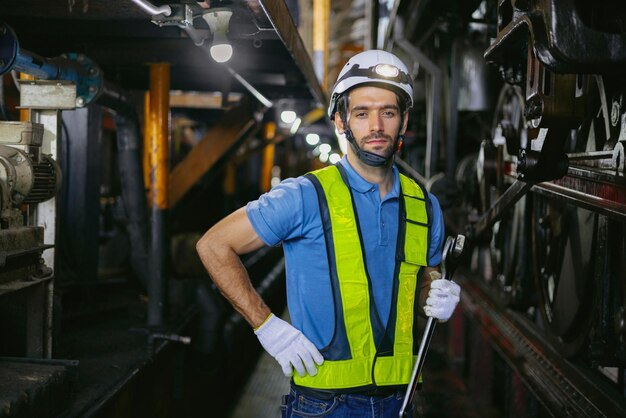 Trabajador industrial sosteniendo una llave para mantener la maquinaria y mirando a la cámara