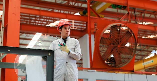 Trabajador de ingeniería de fábrica que opera una máquina de techo de chapa metálica en la fábrica de fabricación de la industria pesada Trabajador en casco de seguridad en las instalaciones industriales de la fábrica