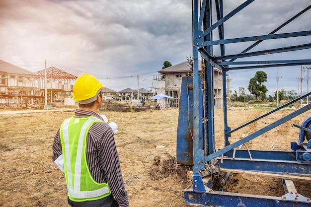 Trabajador de ingeniero de construcción de hombre de negocios asiático en casco protector y papel de planos a mano